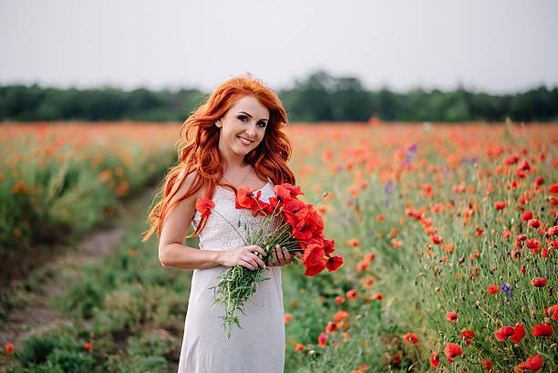 beautiful young woman in poppy field holding a bouquet of poppies, summer